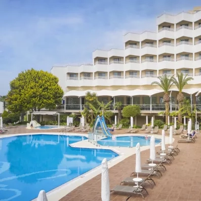 Une grande piscine extérieure bordée de transats au pied d'un hôtel à l'architecture en gradins.