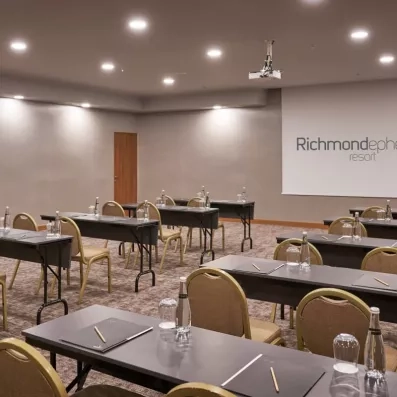 Une salle de conférence moderne, équipée de bureaux individuels et d'un écran.