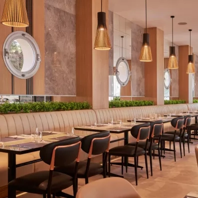 Une salle de restaurant avec des banquettes, des chaises et des luminaires suspendus.