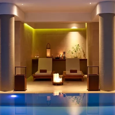 spa, piscine, deux lits avec serviettes, lampe avec lumière tamisée, plante, bougies