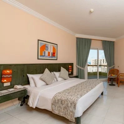 chambre double avec grand lit, tête de lit en bois vert, porte fenêtre avec balcon