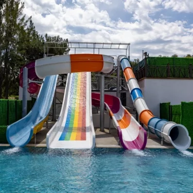 Un ensemble de quatre toboggans aquatiques, plongeant dans une piscine bleue.