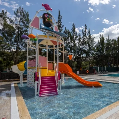 Une aire de jeux aquatiques pour enfants avec un petit toboggan et un seau basculant.