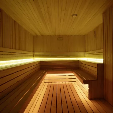 L'intérieur d'un sauna traditionnel en bois clair avec des bancs sur plusieurs niveaux.