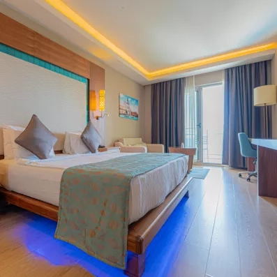 Une chambre lumineuse au mobilier en bois, avec un lit double et d'un balcon.