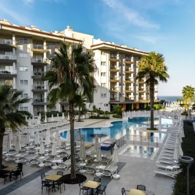 Une grande piscine extérieure entourée de nombreux transats et de palmiers.