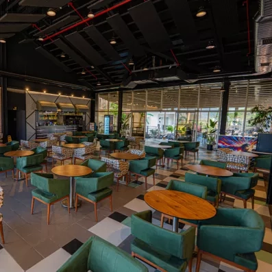 Un vaste espace bar avec de nombreux fauteuils en velours et des tables rondes.