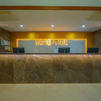 Un comptoir de réception moderne en marbre sombre surmonté d'une enseigne lumineuse.