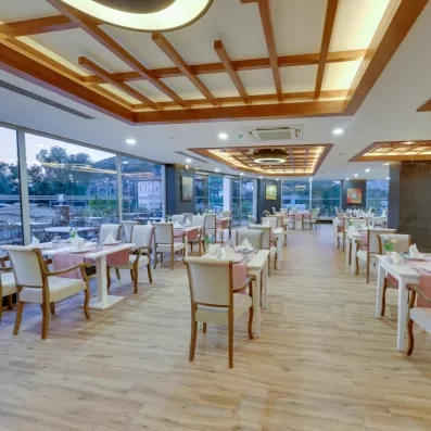 Une salle de restaurant lumineuse et élégante avec de grandes baies vitrées.