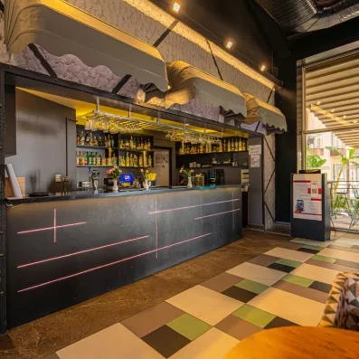 Un bar intérieur au style industriel nocturne, doté de stores gris.