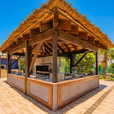 Une station de buffet extérieure abritée sous une structure avec un toit en chaume.