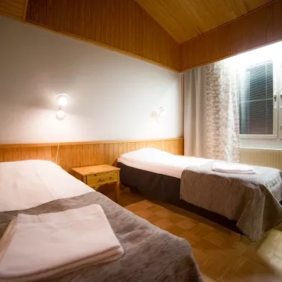 Une chambre simple et chaleureuse avec deux lits séparés et des finitions en bois. 