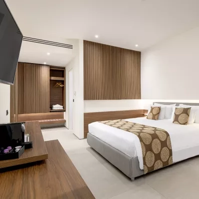 Chambre avec lit double, petite télé posée sur une commode, grand miroir, machine café