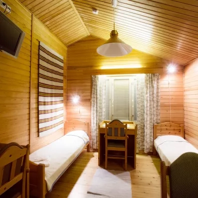 chambre chaleureuse de style chalet, entièrement en bois, avec deux lits simples séparés, un petit bureau sous la fenêtre et une ambiance cosy et lumineuse.