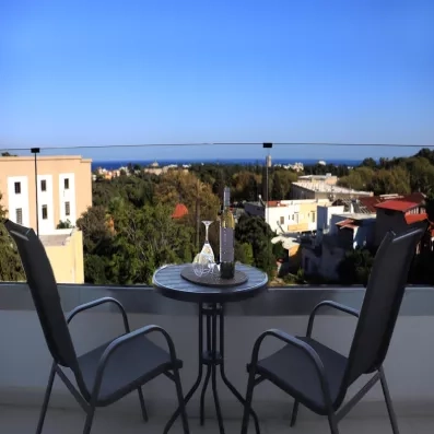 Terrasse, deux chaises et une table, vue sur mer, ciel bleu, bâtiment de l'immeuble