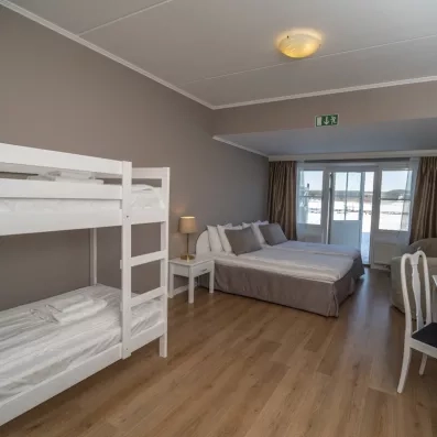 Chambre familiale avec lits superposés et vue sur paysage enneigé, hébergement confort au Grand Arctic Resort.