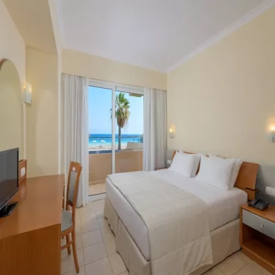 Chambre de l'hôtel avec lit deux places, coiffeuse, porte fenêtre avec balcon et vue sur mer