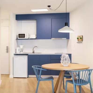 kitchnette avec mini frigo, micro-onde et petite table avec deux chaises bleues
