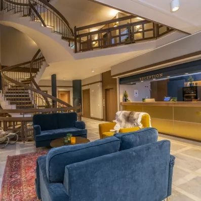 Hall de réception avec escalier monumental et salon confortable, accueil prestigieux pour un séjour luxe en Laponie.