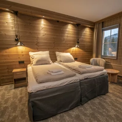 Chambre double lumineuse avec vue sur la forêt enneigée, confort scandinave au cœur de la nature lapone.