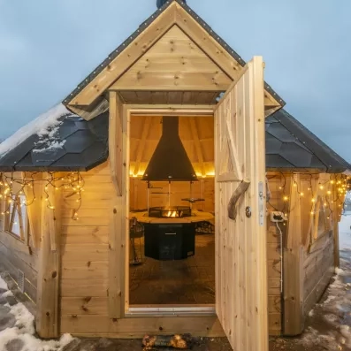 Entrée d'un chalet en bois traditionnel éclairé, refuge chaleureux après une journée d'activités sous la neige.