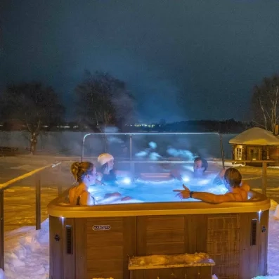 Détente en jacuzzi extérieur sous le ciel étoilé au Grand Arctic Resort, voyage bien-être suédois.