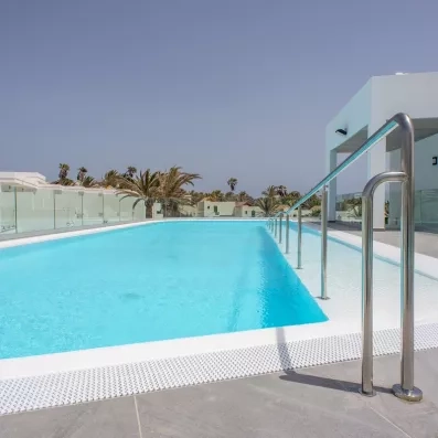 Une piscine surélevée, équipée d'une rampe d'accès, sous un ciel bleu pur.