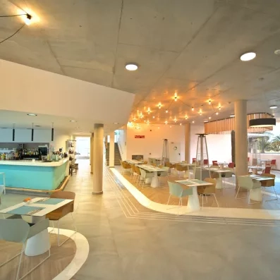 Une vaste salle de restaurant, illuminée par des guirlandes lumineuses chaleureuses.