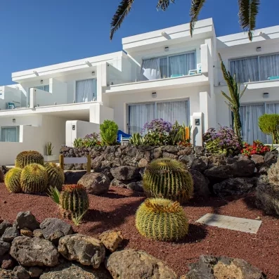 La façade blanche de l'hôtel agrémentée d'un jardin sec composé de cactus.