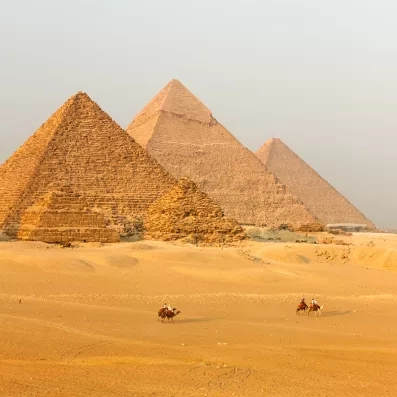 Pyramides de Gizeh au Caire, merveilles de l’Antiquité dans le désert égyptien avec dromadaires au premier plan