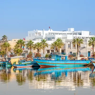 des barques bleues sur l'eau devant des hôtels de bord de mer