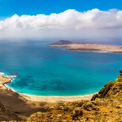 Vue sur l’île de La Graciosa depuis le Mirador del Río à Lanzarote, lagon turquoise, falaises volcaniques et horizon océanique.