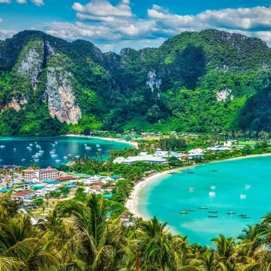 Plage paradisiaque de Koh Phi Phi en Thaïlande, eaux turquoise, falaises calcaires et bateaux traditionnels longtail
