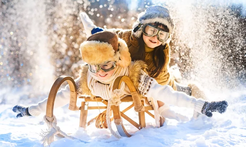 Activités d’hiver en Finlande avec enfants : luge, jeux dans la neige et forêt boréale, vacances famille en Laponie