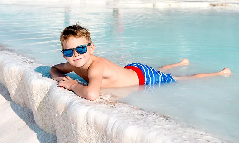 enfant avec des lunettes de soleil se  baignant dans une vasque de calcaire en Turquie à Pamukkale