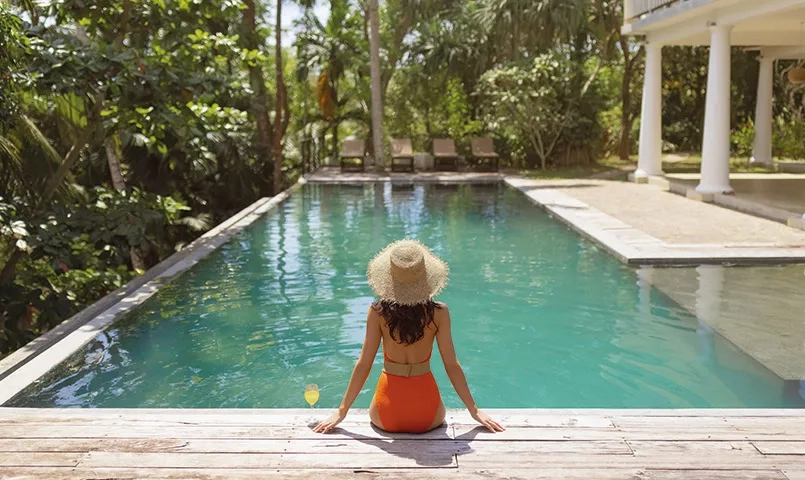 Femme de dos les pieds dans une piscine au calme