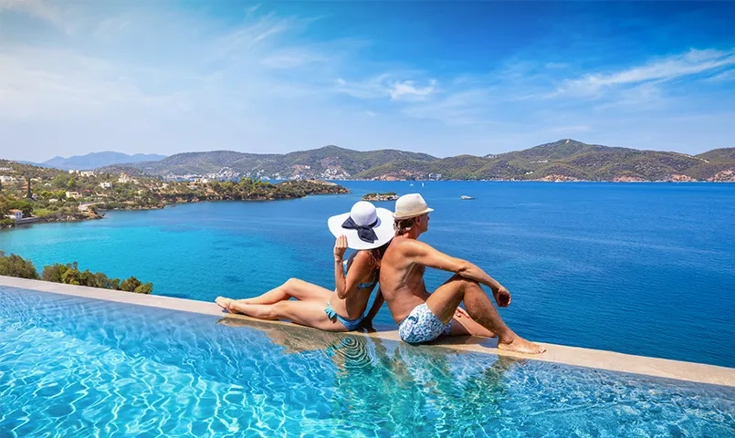 Couple au bord d'une piscine à deversement avec la mer au loin