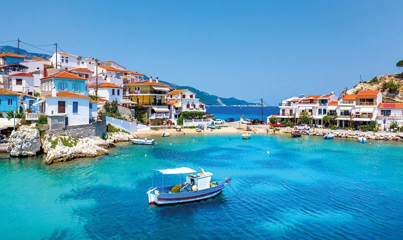 Bateau dans une crique avec un village grec en arrière plan