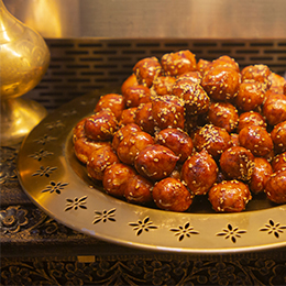 Loukoumades grecs en Crète, beignets dorés nappés de miel et de sésame, pâtisserie traditionnelle méditerranéenne.