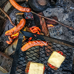 Grillimakkara sur feu de camp en Laponie, saucisses grillées traditionnelles finlandaises en plein air
