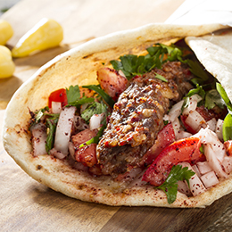 Kebab turc grillé servi dans un pain chaud avec légumes et herbes, spécialité populaire de la street food en Turquie.